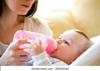 Happy Mother Feeds The Baby Bottle