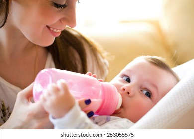 Happy Mother Feeds The Baby Bottle