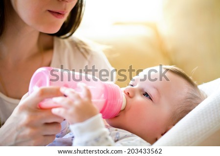 happy mother feeds the baby bottle