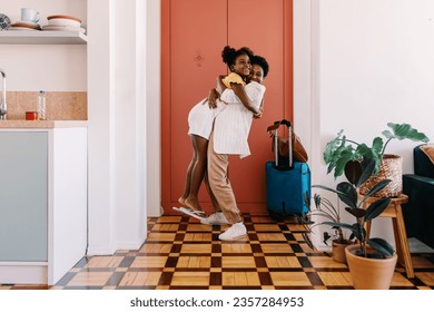 Happy mother greeting her excited daughter after arriving from a trip, lifting her up in a tight hug at the door. Woman reuniting with her child, expressing her love during the warm homecoming. - Powered by Shutterstock