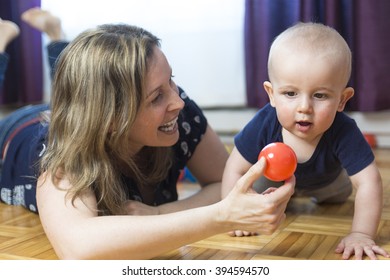 A Happy Mother And Her 1 Year Old Son Playing With Small Ball At Home.