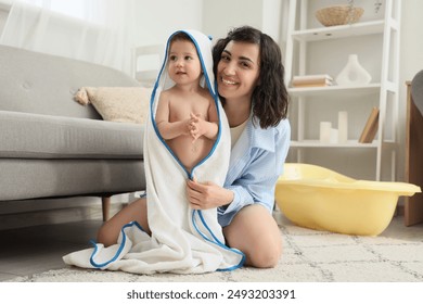 Happy mother with her baby in towel after bathing at home - Powered by Shutterstock