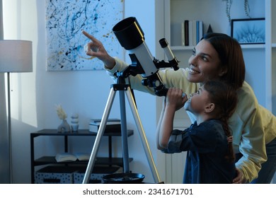 Happy mother and her cute daughter using telescope to look at stars in room - Shutterstock ID 2341671701