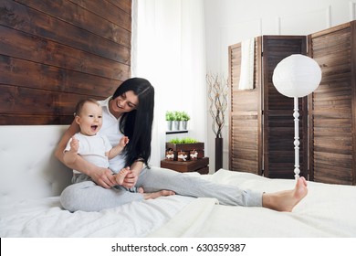 Happy Mother With Her Cute Little Child On The Bed Having A Good Time