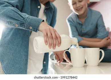 Happy mother and her cute son drinking milk on the kitchen - Powered by Shutterstock