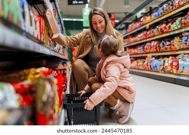 Happy mother and her daughter in grocery store buying candies together. - Powered by Shutterstock