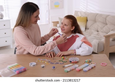 Happy mother with her daughter making beaded jewelry at home - Powered by Shutterstock