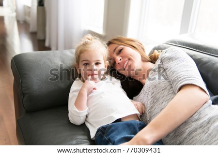 Happy mother with her daughter on the sofa in the living room at home