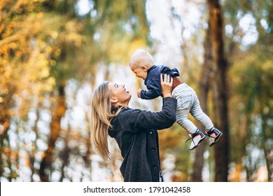 Happy mother with her little baby son have fun in the city park with colorful leaves around in autumn time. Happy family, mother’s day concept - Shutterstock ID 1791042458