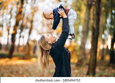 Happy mother with her little baby son have fun in the city park with colorful leaves around in autumn time. Happy family, mother’s day concept - Shutterstock ID 1805494753