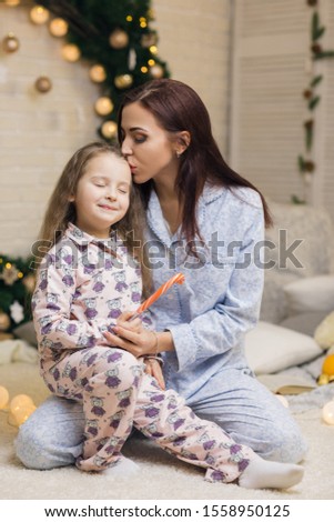 happy mother with her little child daughter playing near the Christmas tree