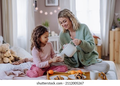 Happy mother with her little daughter having breakfast together in bed at home. - Powered by Shutterstock