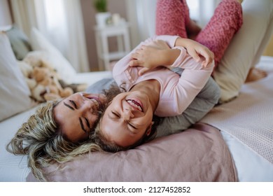 Happy mother with her little daughter hugging and having fun together on bed at home. - Powered by Shutterstock