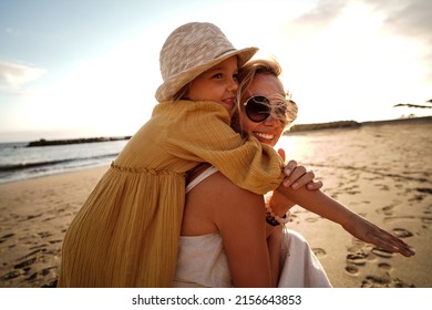 Happy Mother With Her Little Daughter Having Fun Together On The Beach, Playing And Hugging. Family Summer Vacations. Mother's Day. Children's Day. Real People Emotions.