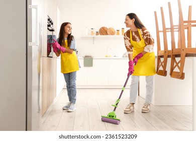 Happy mother with her little daughter cleaning in kitchen - Powered by Shutterstock