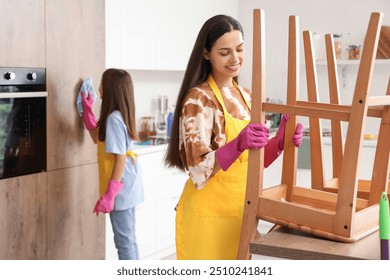 Happy mother with her little daughter cleaning in kitchen - Powered by Shutterstock