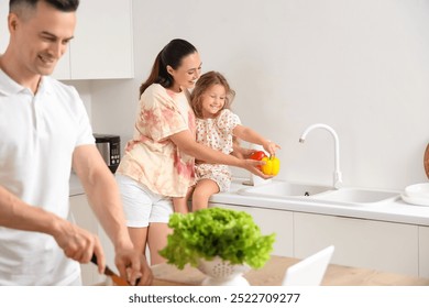 Happy mother with her little daughter washing bell peppers in kitchen - Powered by Shutterstock