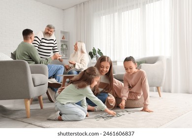 Happy mother with her little daughters doing puzzle at home - Powered by Shutterstock