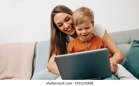 Happy mother with her little son enjoying in online shopping or working from home. Business from distance and virtual communication.