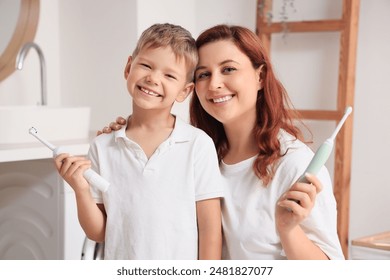 Happy mother and her little son with electric toothbrushes in bathroom - Powered by Shutterstock