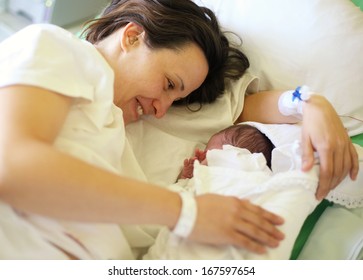 Happy Mother With Her Newborn Baby On Hospital Bed