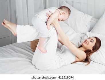 glückliche Mutter und ihr einjähriges Baby im Bett zu Hause
