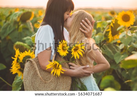 Happy mother and her teenager daughter in the sunflower field. Outdoors lifestyle happiness. Summer fun. Mother's Day concepts