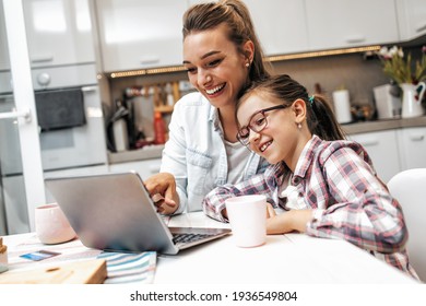 Happy Mother With Her Young Daughter Enjoying In Online Shopping Or Working From Home. Business From Distance And Virtual Communication With Family And Friends.