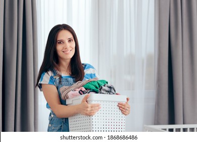 Happy Mother Holding A Basket Of Dirty Laundry In Nursery Room. New Mom Feeling Energized Dealing With Household Chores
