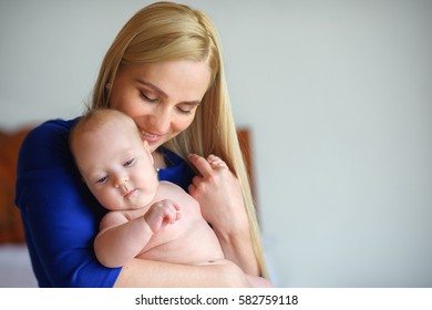 happy mother holds on hands and gently presses to a breast of the newborn baby, motherhood