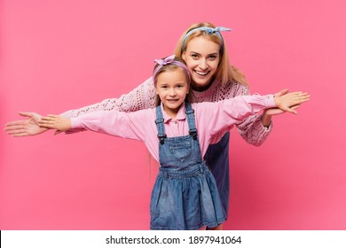 Happy Mother And Kid Smiling While Standing With Outstretched Hands Isolated On Pink