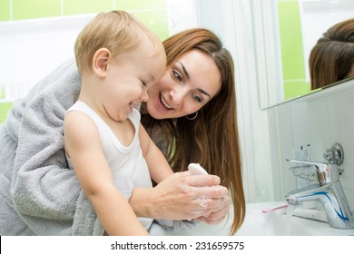 Happy Mother And Kid Wash Hands With Soap In Bathroom