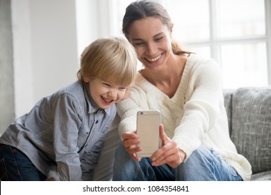 Happy Mother Laughing Taking Selfie With Little Son On Smartphone At Home, Smiling Single Mom And Cute Adopted Boy Playing Making Photo Posing For Self Portrait, Mommy And Kid Watching Video On Cell