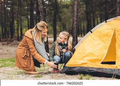 happy mother and little daughter installing camping tent in forest - Powered by Shutterstock