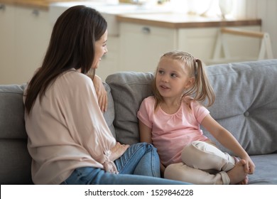 Happy Mother And Little Daughter Talking, Sharing News, Sitting On Comfortable Couch In Living Room, Young Mum And Adorable Preschool Girl Chatting, Family Spending Weekend Together At Home