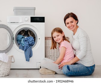 Happy Mother And Little Daughter Washing Clothes