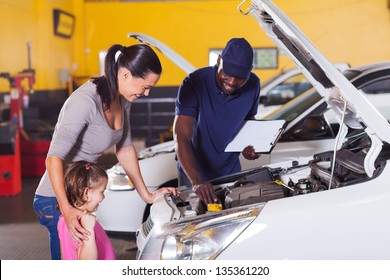 happy mother and little girl in car service center with auto technician