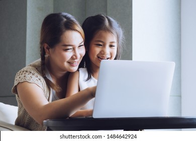 Happy Mother With Little Kid Daughter Using Laptop At Home