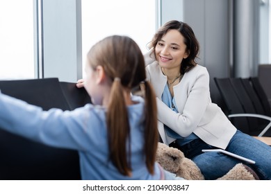 Happy Mother Looking At Blurred Daughter In Airport Lounge