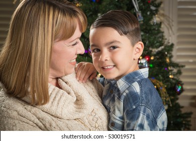 Happy Mother and Mixed Race Son Hug Near Their Christmas Tree.