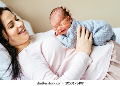 Happy Mother With Newborn Baby, Close Up Portrait Parent Lying With Her Crying New Born Baby On Stomach. Mother's Day Concept