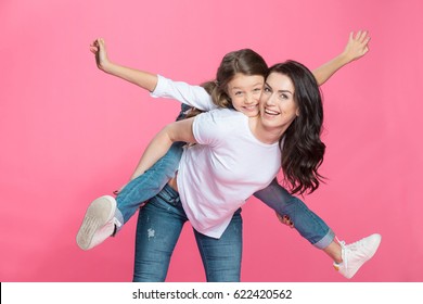 Happy mother piggybacking adorable little daughter smiling at camera - Powered by Shutterstock