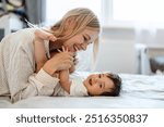 Happy mother playing with her baby daughter at home
