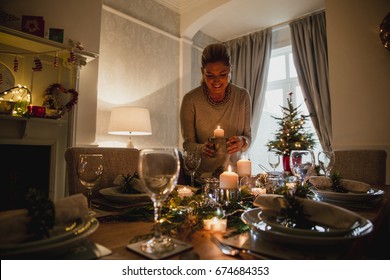 Happy Mother Is Setting The Table For Christmas Dinner With Her Family.  She Is Lighting Candles.