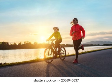 Fröhliche Mutter und Sohn gehen im Freien Sport. Junge fährt mit dem Fahrrad in Helmen, Mutter rennt am sonnigen Tag. Familie Silhouette bei Sonnenuntergang. Frische Luft. Gesundheitsversorgung, Authentizität, Gleichgewicht und Ruhe