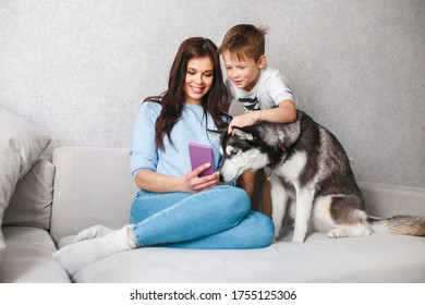 Happy mother and son at home petting their dog and taking selfie