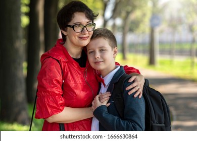 Happy Mother And Son Hug Each Other. Mom And Teen Son In The Park After School. Happiness And Love In The Family.