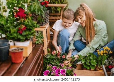 Happy mother and son planting flowers in home garden. Cheerful mom and boy spending time together, gardening at city balcony. Mom and kid work together to plant and care for urban garden on terrace. - Powered by Shutterstock