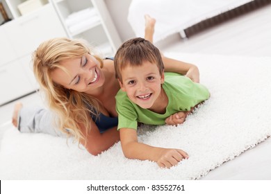 Happy mother and son playing in the living room wrestling on the floor - Powered by Shutterstock