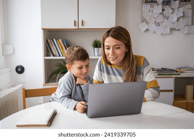 Happy mother and son using laptop together at home - Powered by Shutterstock